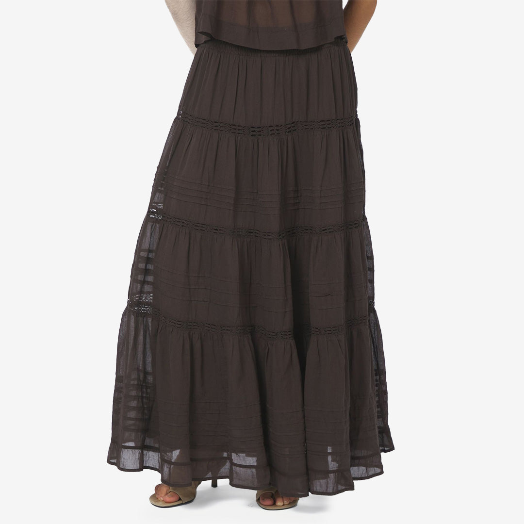 Felicia S Voile Skirt i mörkbrun färg, maxi-kjol i bomull med smockmidja och dekorativa banddetaljer.