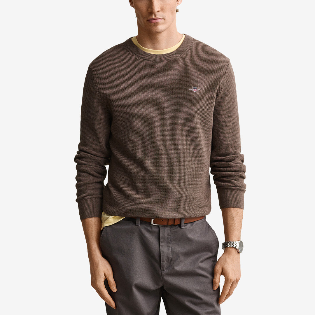Stickad herrtröja från Gant i dk hazelnut melange med rund hals, våffelstruktur och broderad logotyp på bröstet.