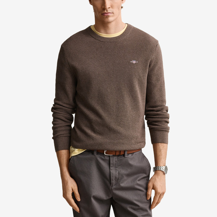 Stickad herrtröja från Gant i dk hazelnut melange med rund hals, våffelstruktur och broderad logotyp på bröstet.