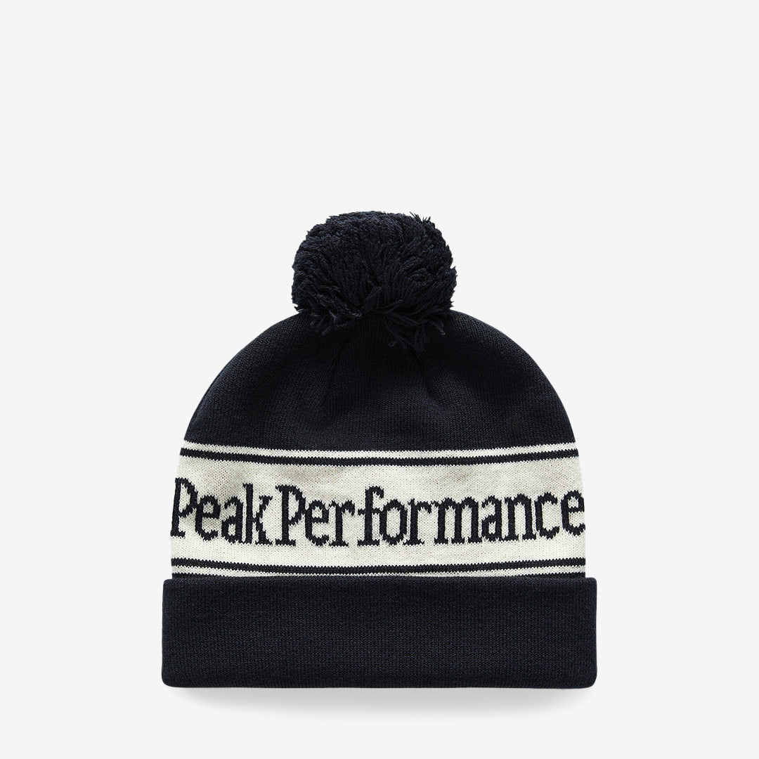 Peak Performance Pow Hat mössa i Black/Vintage White med ränder, logotyp och boll på toppen.
