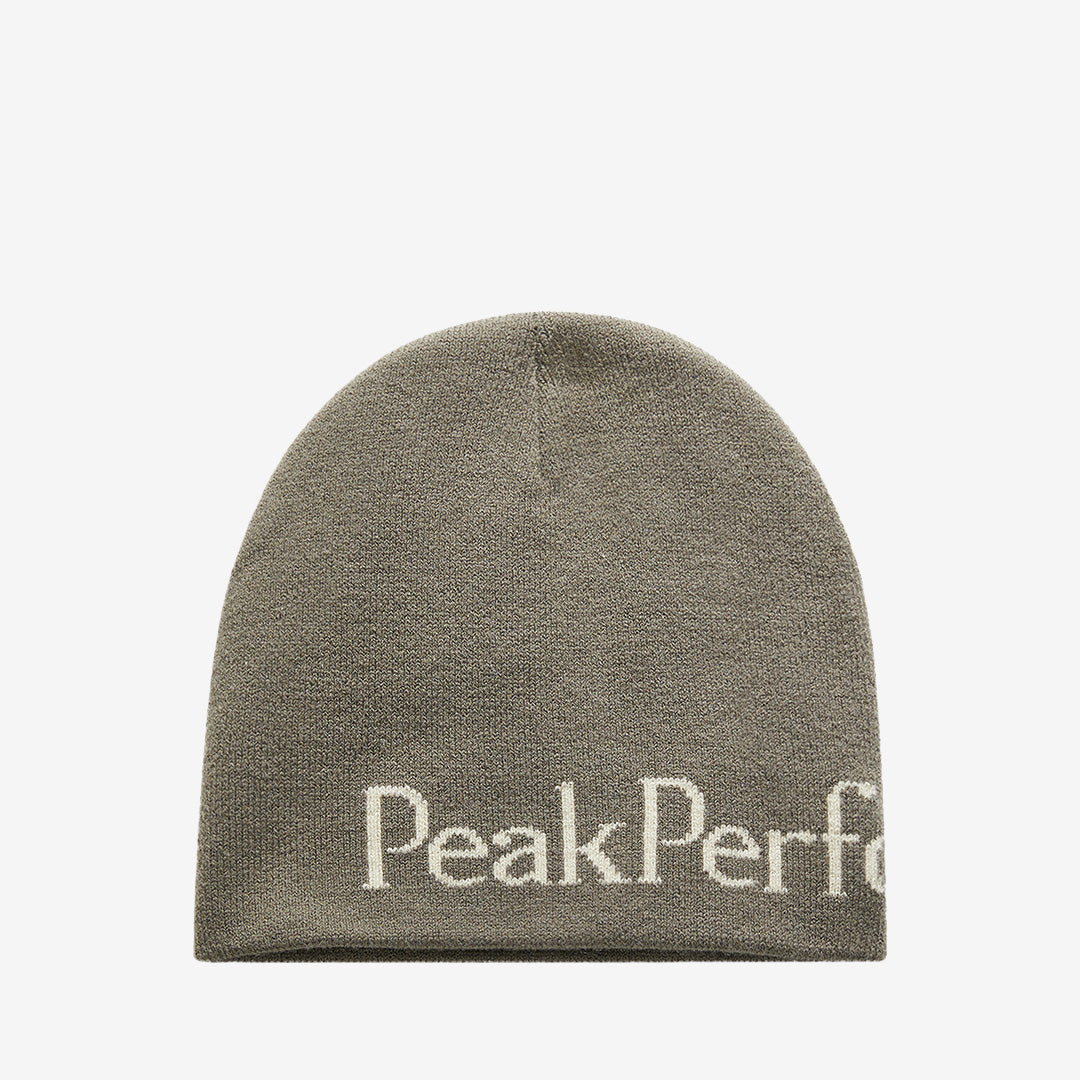 Peak Performance ribbstickad mössa i Terrain Tan/Sand Fog med klassiskt ribbstickat mönster och Peak Performance-logga framtill.